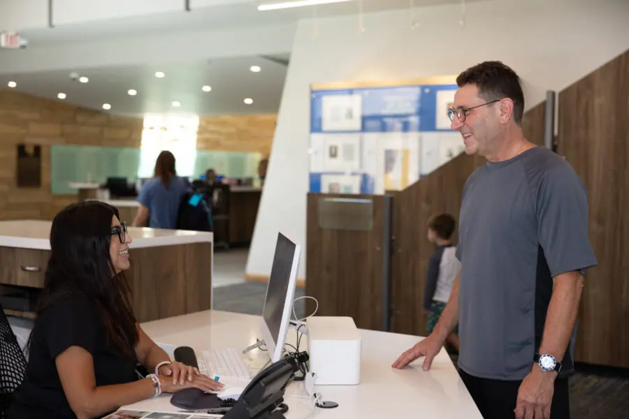 A woman at the front desk is chatting with a man in gym clothes at the entrance to the J.