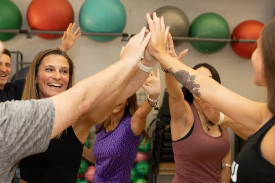 A group of people high-five after a workout in a gym.