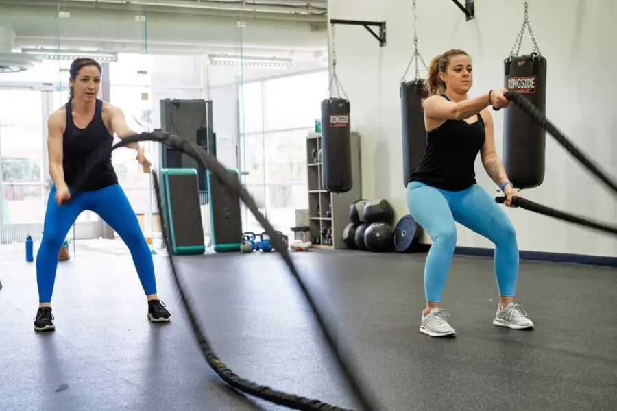 Two women move heavy ropes in a Cross train class.