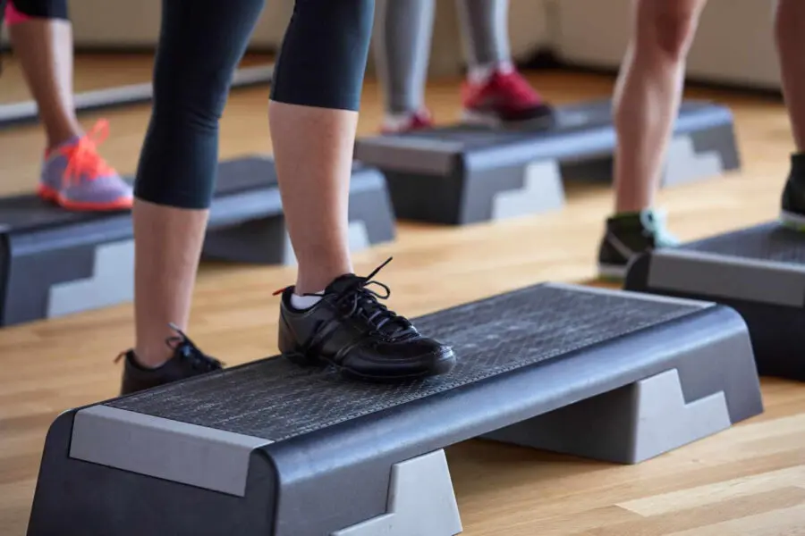 A close up of sneakers on a plastic step for exercise.