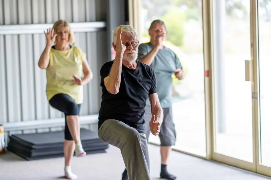 Older adults practice Tia Chi in a bright studio.