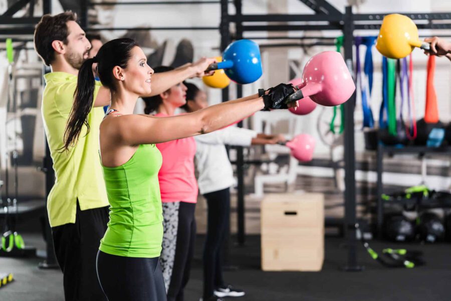 Several adults practice HIIT with large barbel weights.