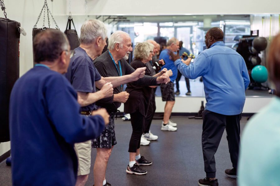 A group of Silver Sneakers learn boxing form from an instructor.